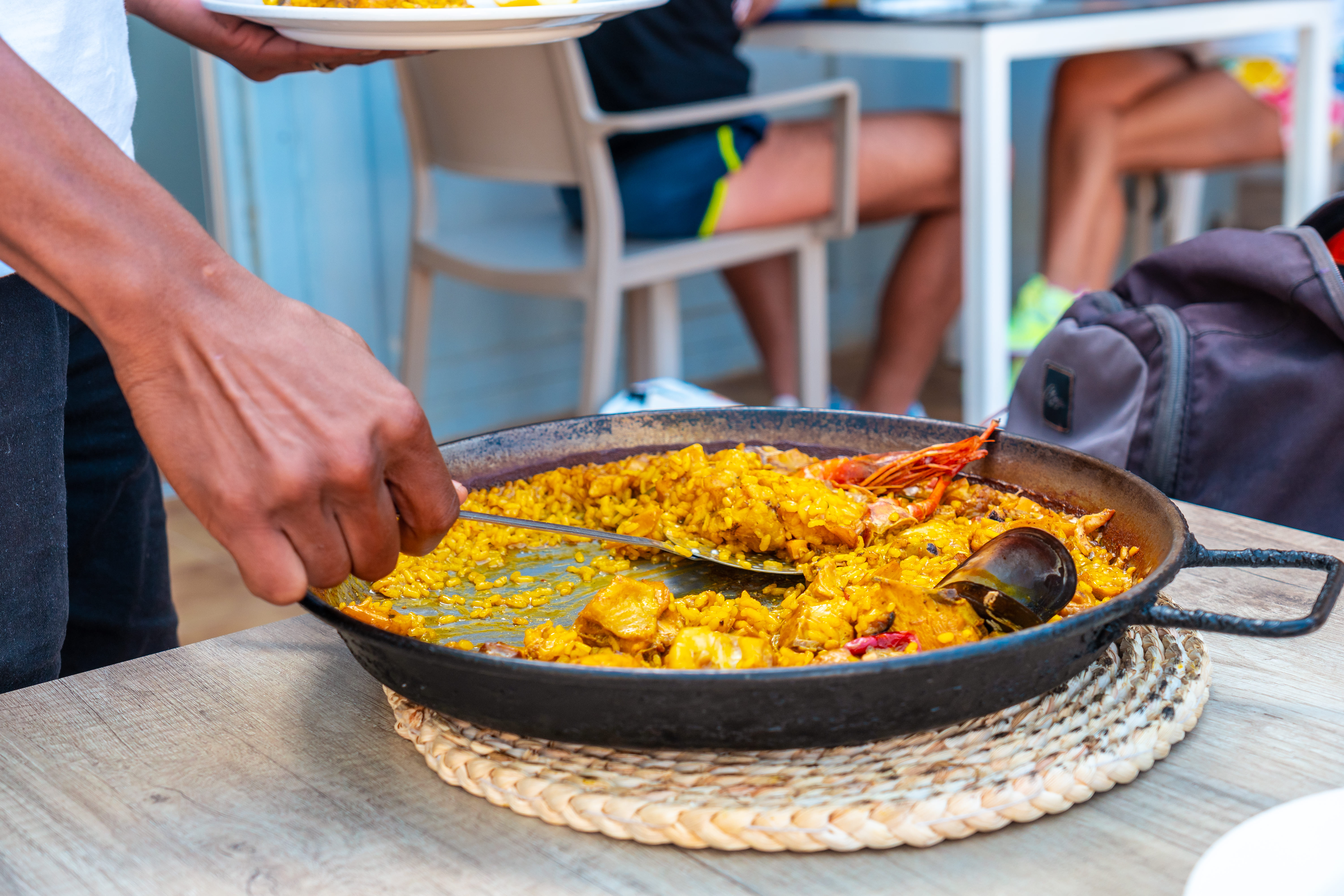 Paella tradicional humeante sobre mesa rústica en Majadahonda, rodeada de ingredientes frescos típicos de la receta auténtica.