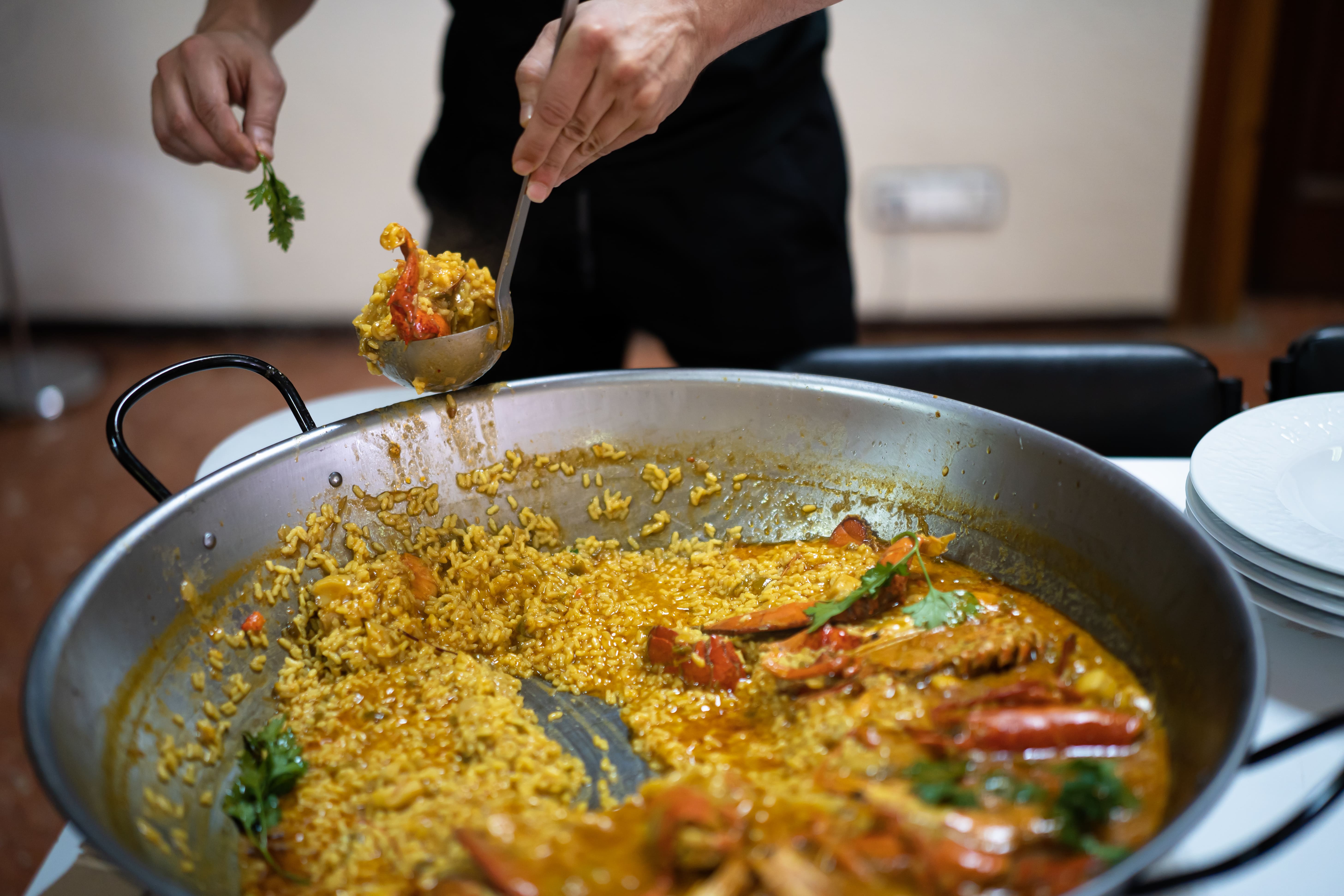 Interior de arrocería en Majadahonda con varias paellas grandes recién hechas y comensales disfrutando de una comida especial.